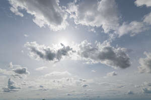 pale blue sky with sun peeking from behind a cloud