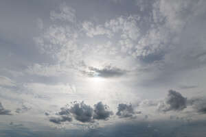 pale grey sky with sun behind a small cloud