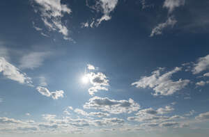 bright sky with sun and small clouds