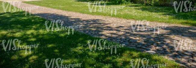 cobblestone road between grass fields