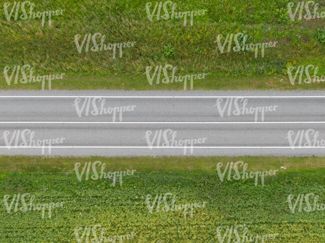 aerial view of an asphalt road between grasslands