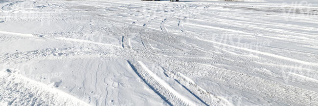 sunny field of snow with tyre tracks