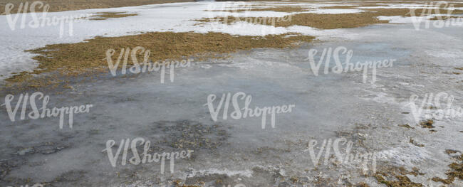 field of grass with partches of snow and ice