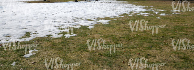 grass field partially covered in snow