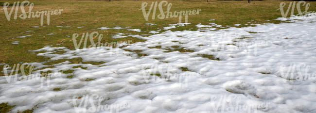 lawn in early spring partially covered with snow