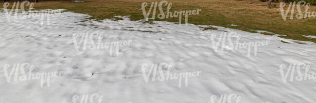 grass field with large patch of snow