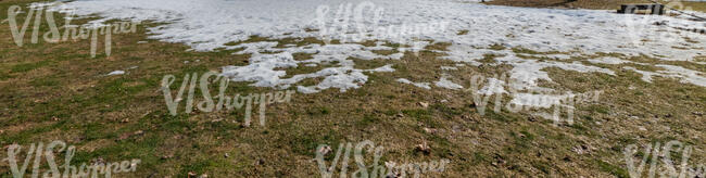 grass field with patches of melting snow