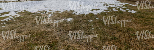 field of grass with last patches of melting snow