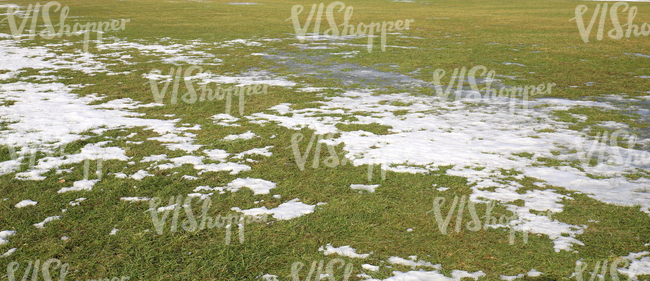 grass field partially covered with snow and ice