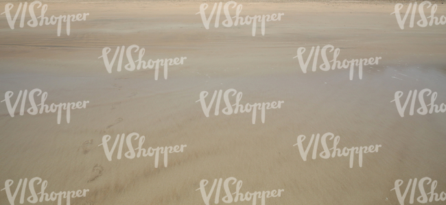 sandy beach with footprints and partially covered with water