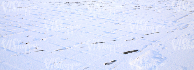 snow covered pavement with footprints