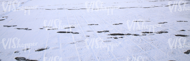 snow covered pavement with footprints