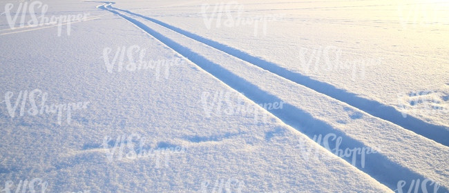 snow covered ground with vehicle tracks