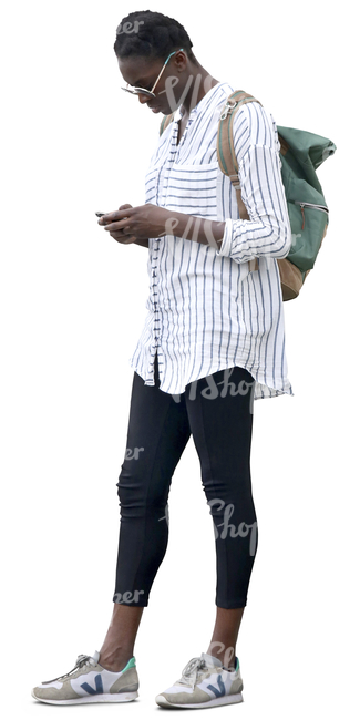 black woman in a striped white shirt standing and looking at her phone