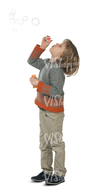 young boy standing and blowing bubbles