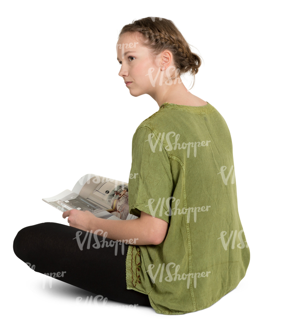 teenage girl sitting on a floor and reading a magazine