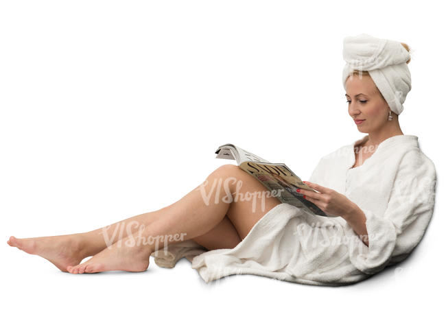 woman in a white bathrobe sitting and reading a magazine