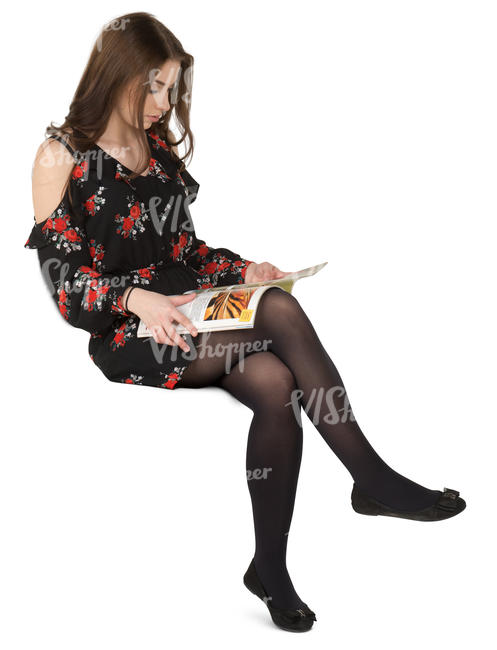 woman in a dress sitting and reading a magazine