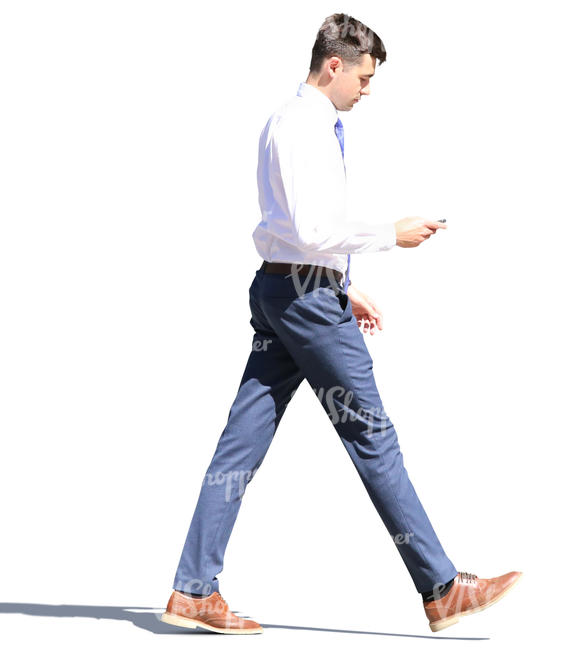 young businessman walking and looking at his phone
