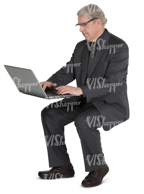 older businessman sitting at the desk and working with laptop