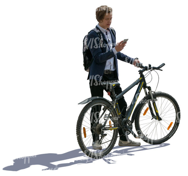 backlit teenage boy standing with a bike