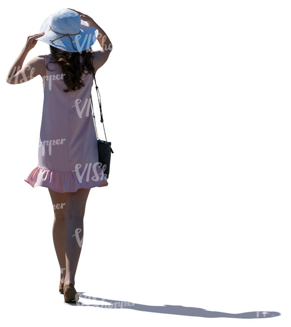 backlit woman in a pink summer dress walking