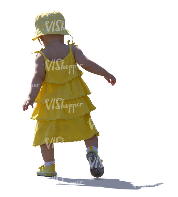 backlit baby girl in a yellow dress walking