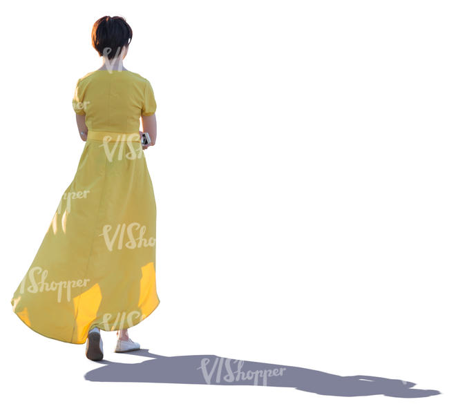 backlit woman in a long yellow dress walking