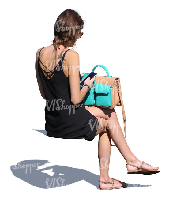 woman in a black summer dress sitting and checking her phone