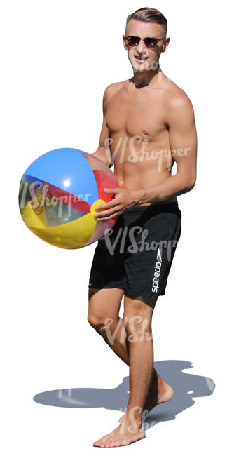 man at the beach walking and holding a ball