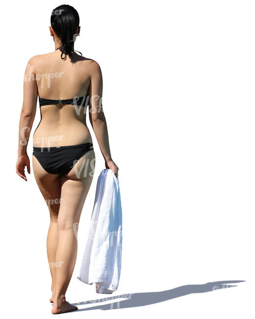 woman in a black bikini walking with a towel in her hand