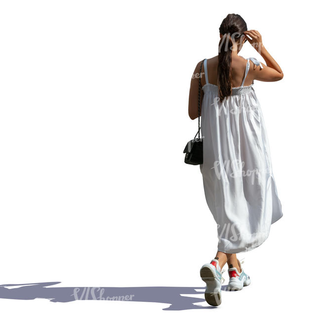 sidelit woman in a white summer dress walking