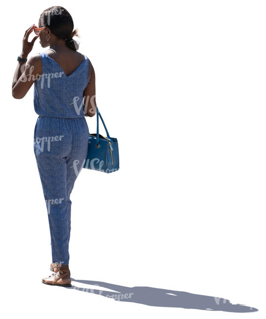 backlit woman in a blue jumpsuit standing