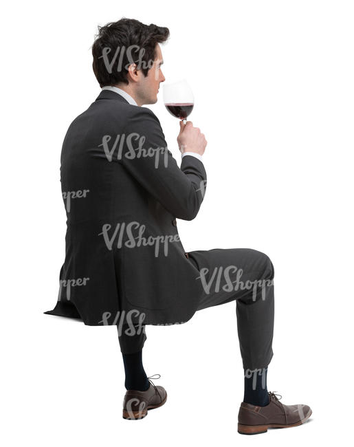 man in a suit sitting and drinking wine