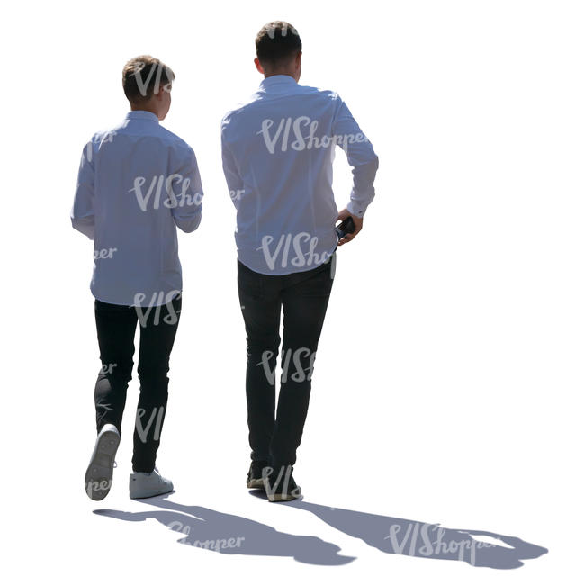 two backlit teenage boys walking