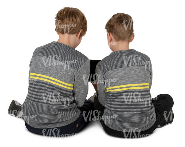 two boys sitting on the floor and looking at a tablet