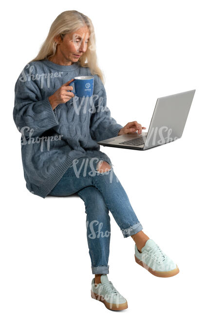 senior woman drinking coffee and looking at laptop