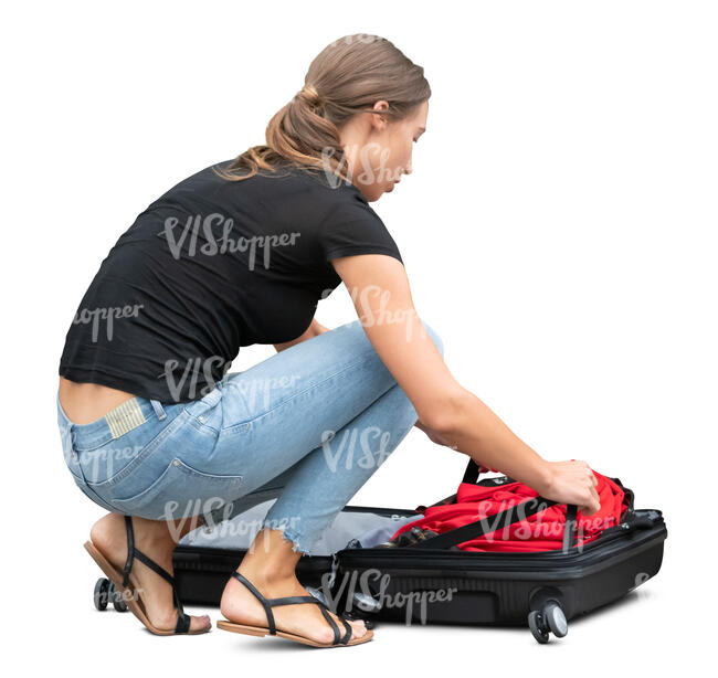 woman squatting and packing her suitcase