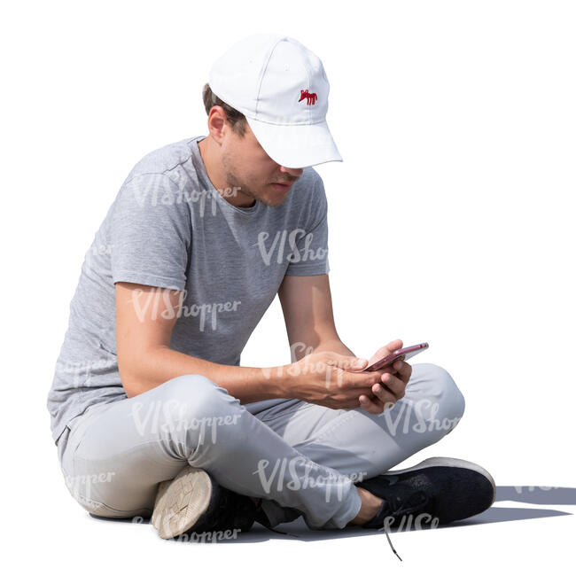 young man sitting on the ground and texting