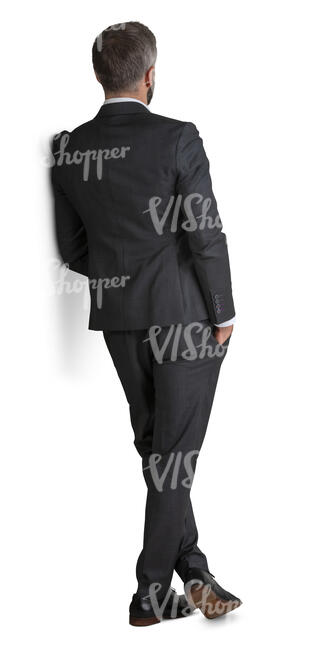 man in a suit standing and leaning against the wall