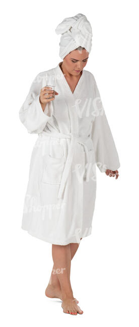 woman in a bathrobe walking and holding a glass of water