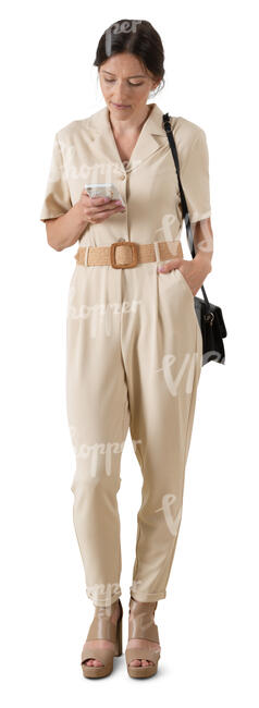 cut out woman in a beige jumpsuit standing and checking her phone