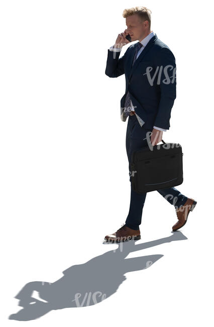 cut out backlit businessman walking and talking on a phone