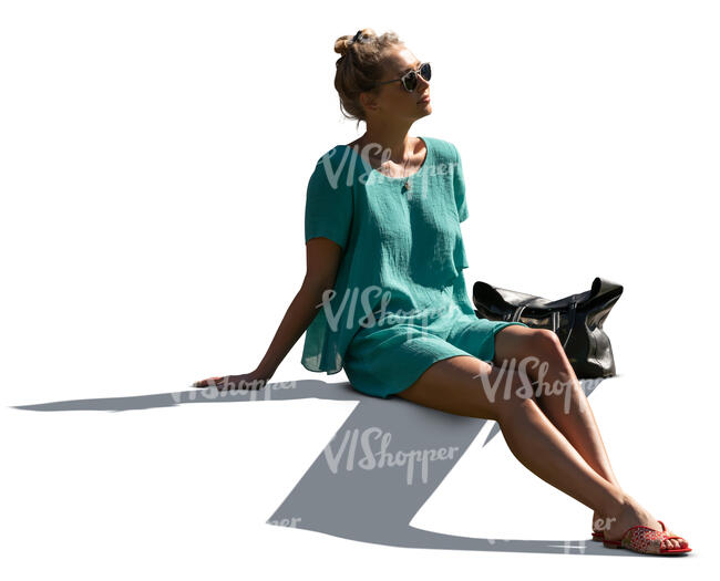 cut out sidelit woman in a green summer dress sitting