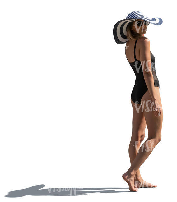 sidelit woman in a swimsuit and wearing a big summer hat standing