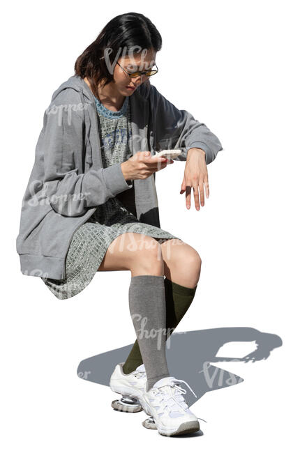 cut out woman sitting at a table and looking at her phone
