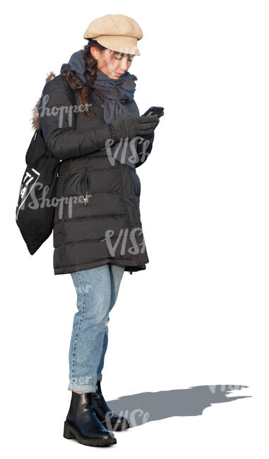 woman in a winter overcoat standing and texting