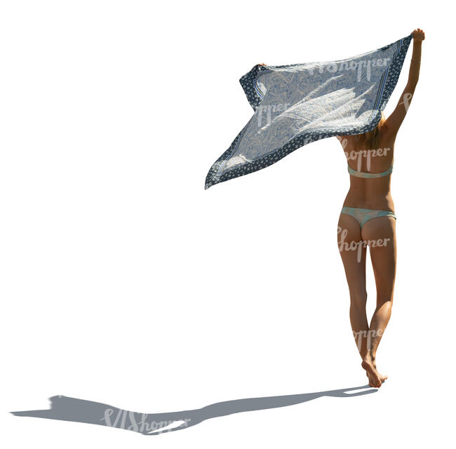 cut out backlit woman in bikini walking on the beach and holding towel in the air