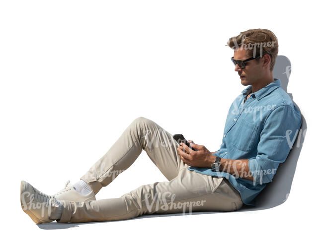 cut out young man sitting outdoors and looking at his phone