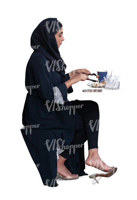 cut out muslim woman sitting in a cafe and eating